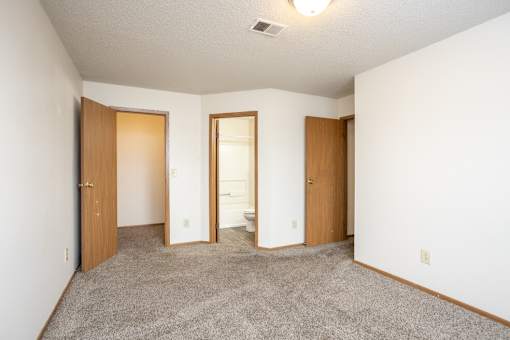 A room with three doors and a carpeted floor.