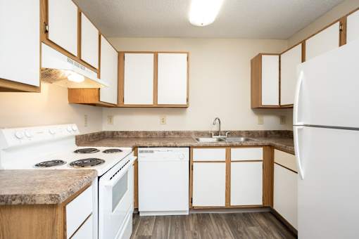 A kitchen with white appliances and wooden cabinets.
