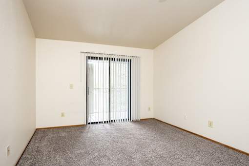 A room with a carpeted floor and a sliding glass door.