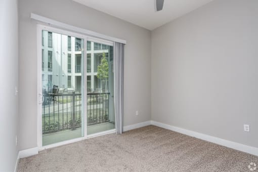 A room with a sliding glass door leading to a balcony.