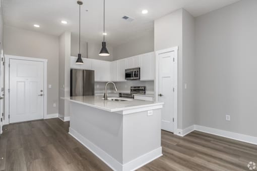 A kitchen with a white island and pendant lights.
