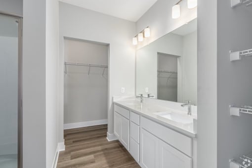 A bathroom with a sink, mirror, and wooden floor.