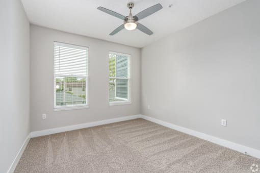 A room with a ceiling fan and carpeted floor.