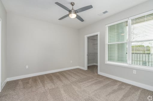 A room with a ceiling fan and carpeted floor.