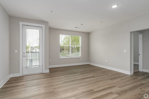 A room with a wooden floor and a window with blinds.
