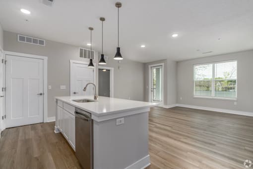A kitchen with a white countertop and wooden flooring.
