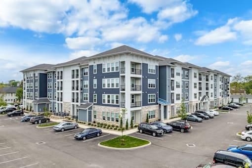 A large apartment complex with a parking lot in front.