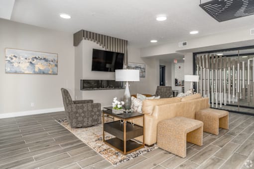 A living room with a grey sofa, a grey armchair, a coffee table and a painting on the wall.