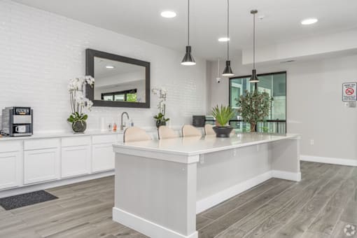 A white kitchen with a large island and a mirror above it.