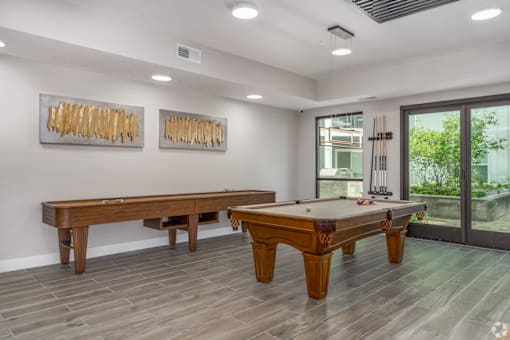A room with a pool table and two paintings on the wall.