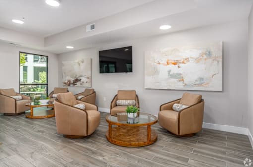 A living room with a large painting on the wall and four chairs around a coffee table.