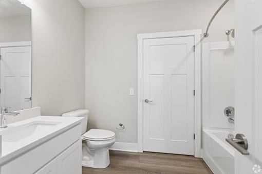 Bathroom with quartz countertops, closet, and bath/shower of an apartment unit.
