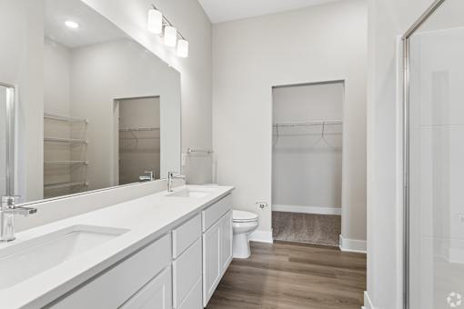 Bathroom with quartz countertops, closet, and bath/shower of an apartment unit.