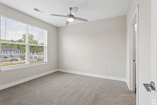 Carpeted bedroom with ceiling fan of a Tiffany Flats apartment home.