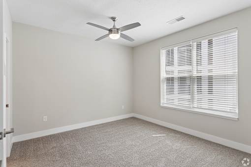 Carpeted bedroom with ceiling fan of a Tiffany Flats apartment home.