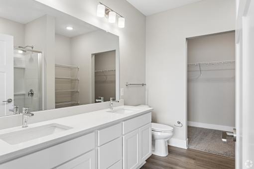 Bathroom with quartz countertops, closet, and bath/shower of an apartment unit.