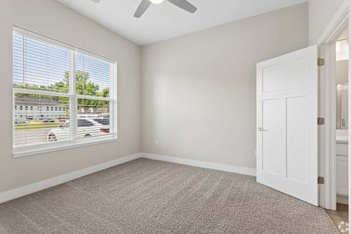 Carpeted bedroom with ceiling fan of a Tiffany Flats apartment home.