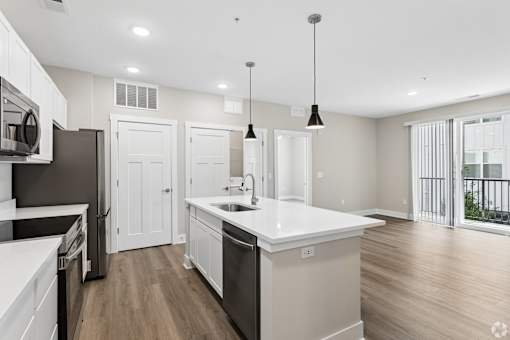 Kitchen with quartz countertop, refrigerator, stove, oven, dishwasher, and microwave, and the living area, of an apartment unit at Tiffany Flats in Columbus, OH.