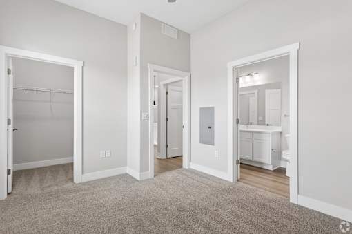 Carpeted bedroom, closet, and attached bathroom with ceiling fan of a Tiffany Flats apartment home.