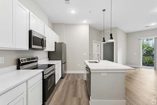 Kitchen with appliances and living area of an apartment home at Tiffany Flats in Columbus, OH.