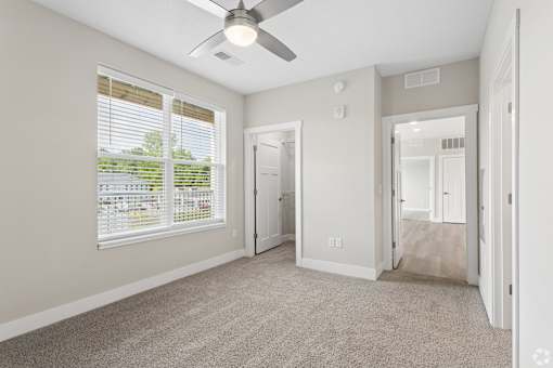 Carpeted bedroom and closet with ceiling fan of a Tiffany Flats apartment home.