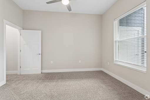 Carpeted bedroom with ceiling fan of a Tiffany Flats apartment home.