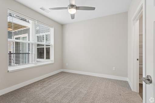 Carpeted bedroom with ceiling fan of a Tiffany Flats apartment home.
