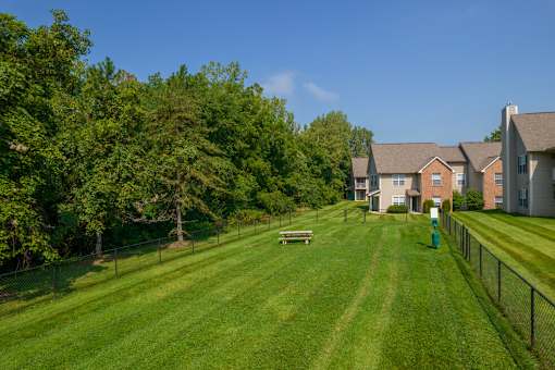 A grassy field with a fence and a building in the background.