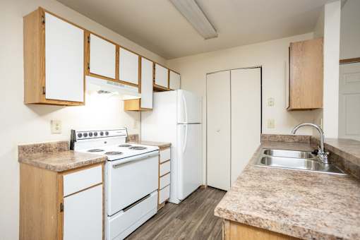 A kitchen with white appliances and wooden cabinets.