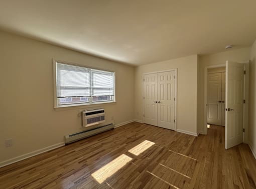 A room with wooden floors and a window with blinds.