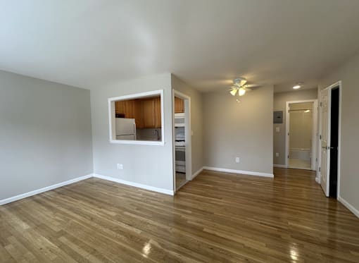 A room with wooden floors and a small kitchenette in the corner.