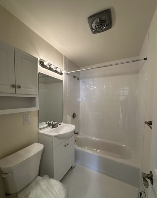 A white bathroom with a toilet, sink, and bathtub.