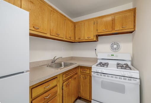 A kitchen with a white stove and wooden cabinets.