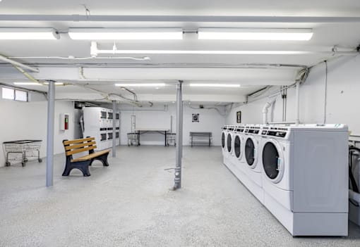 A laundromat with a row of washing machines and a bench.