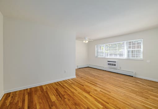 A room with wooden floors and a window with blinds.