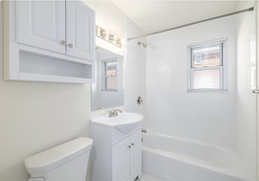 A white bathroom with a toilet, sink, and bathtub.