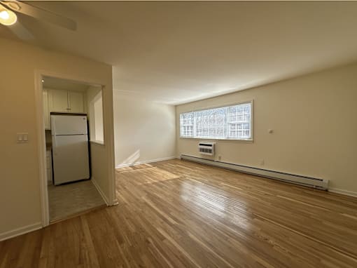 A room with wooden floors and a window with blinds.