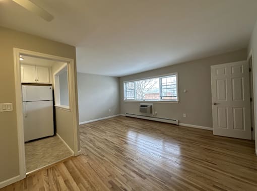 A room with wooden floors and a window with blinds.