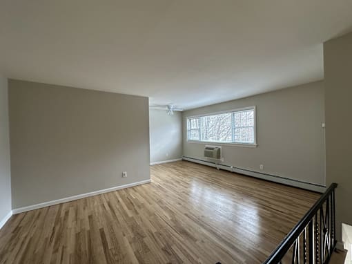 A room with wooden floors and a window with blinds.