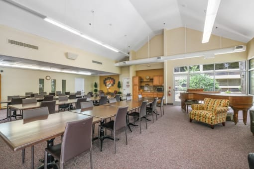 community room with rows of tables and chairs and a piano at Sundale Manor Apartments