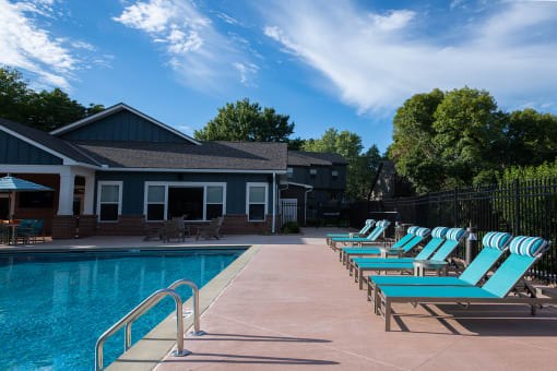 a swimming pool with chaise lounge chairs and clubhouse in the background