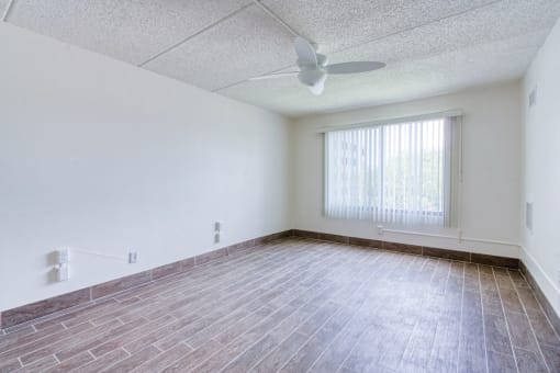 spacious bedroom with ceiling fan, large windows, and hardwood-style floors