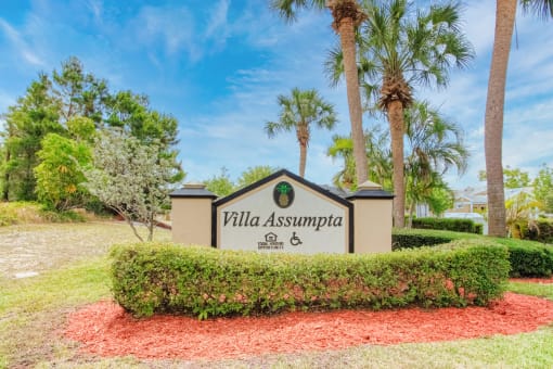 Monument signage with shrubs and palm trees