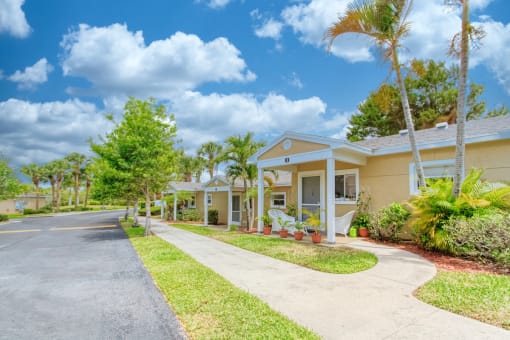 trim landscaping, neat sidewalks, and mature landscaping in front of villas