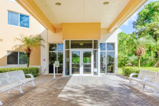 glass front entrance under covered walkway with benches for seating