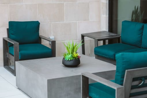outdoor seating area with 3 blue lounge chairs around a square gray table at The Apex at CityPlace, Overland Park