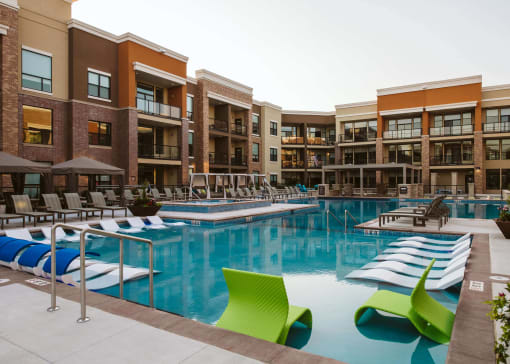 The outdoor pool at an apartment home surrounded by chairs at The Apex at CityPlace, Overland Park