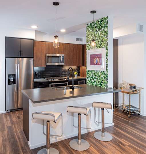Kitchen with stainless steel appliances and bar stools at Vida North Park, San Diego, California