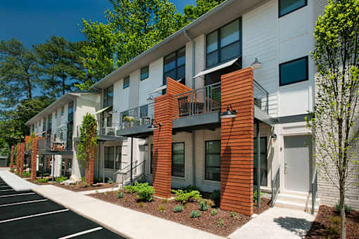 A row of modern townhouses with balconies and front yards.