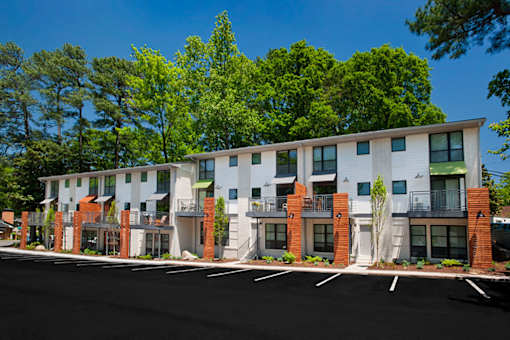 A row of modern townhouses with balconies and trees in the background.